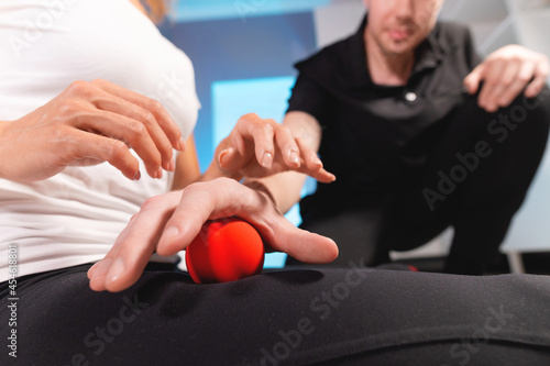 Physiotherapist teaches self-massage with red balls, patient with leg injury. Treatment of sports injuries. Practical use. Rehabilitation concept.