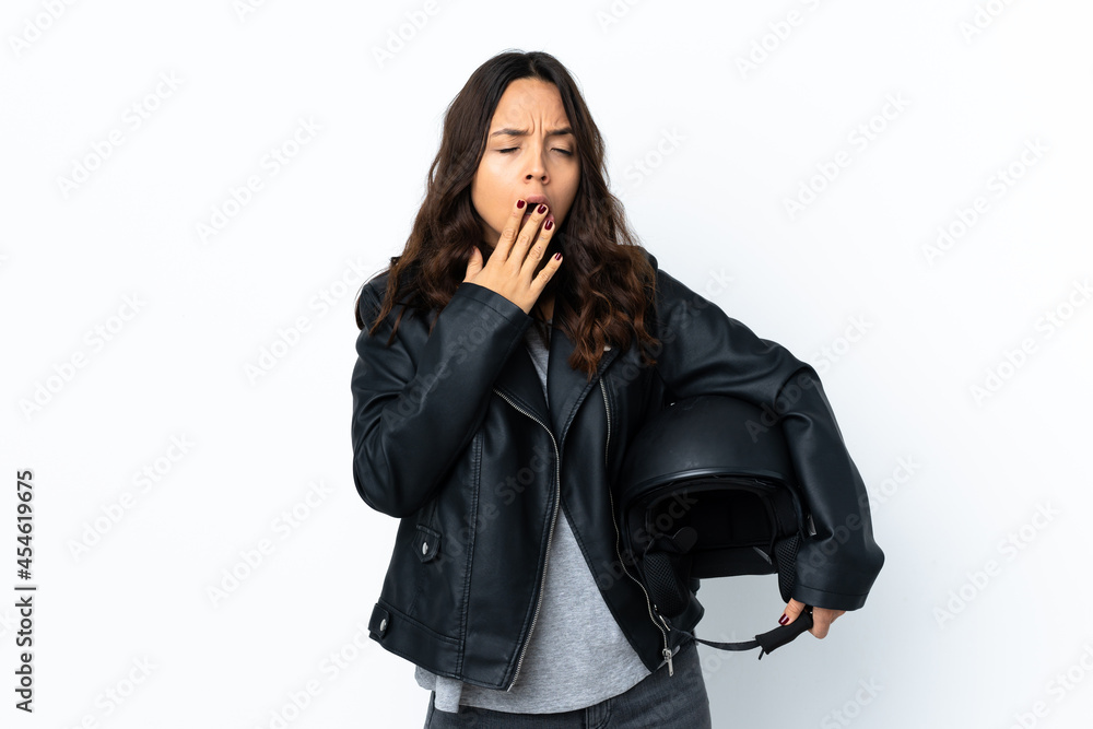 Young woman holding a motorcycle helmet over isolated white background yawning Young woman holding a motorcycle helmet over isolated white background yawning