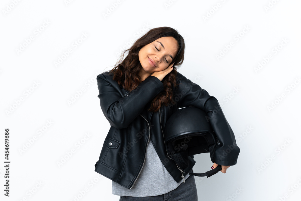 Young woman holding a motorcycle helmet over isolated white background making sleep gesture in dorable expression Young woman holding a motorcycle helmet over isolated white background making sleep gesture in dorable expression