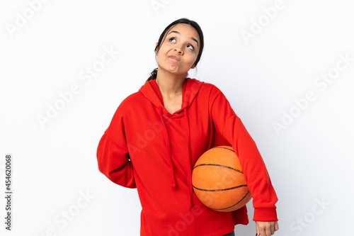 Young woman playing basketball over isolated white background and looking up © luismolinero