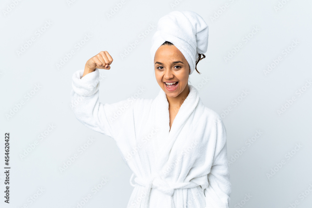 Young woman in bathrobe over isolated white background doing strong gesture Young woman in bathrobe over isolated white background doing strong gesture