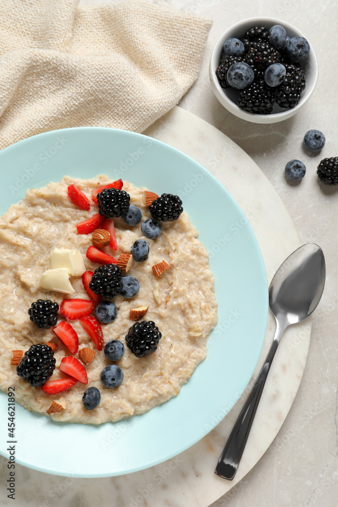 Tasty oatmeal porridge with berries and almond nuts served on light table, flat lay Tasty oatmeal porridge with berries and almond nuts served on light table, flat lay