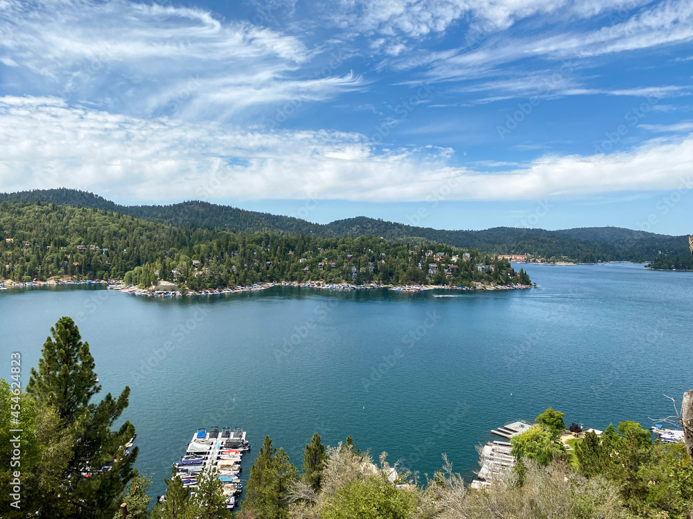 Wide angle view overlooking large mountain lake with marina and blue sky cloudscape