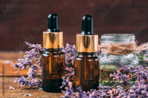 Two transparent brown jars of lavender oil on a wooden table.