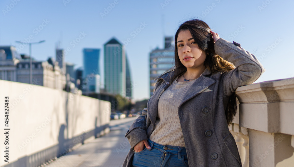 Young Latin woman looking at camera, posing on a bridge in the city.