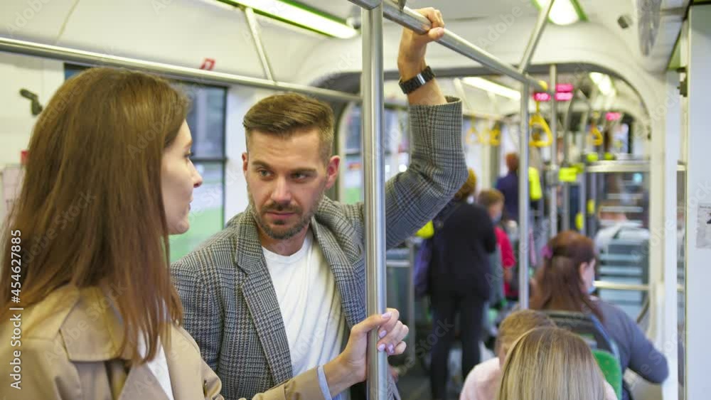 Waist up view of two friends man and woman standing at the public transport and chatting with each other. People having friendly conversation during the road Waist up view of two friends man and woman standing at the public transport and chatting with each other. People having friendly conversation during the road