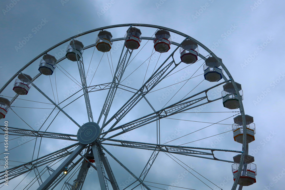 Ferris wheel spinning in an amusement park. Fairground ride.  Cabins of the ferris wheel. 