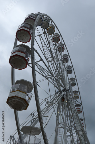 Ferris wheel spinning in an amusement park. Fairground ride. Cabins of the ferris wheel. 