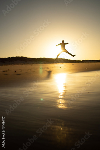 person jumping on the beach at sunset