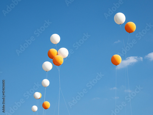 Large white and orange balloons fly in the sky