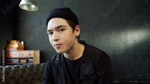 Portrait of a teenage guy in black hat and black shirt on a black background