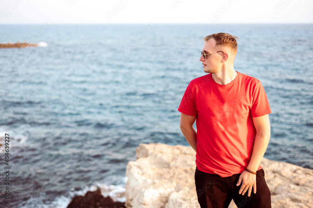 young man standing on the sea coast, portrait on summer day