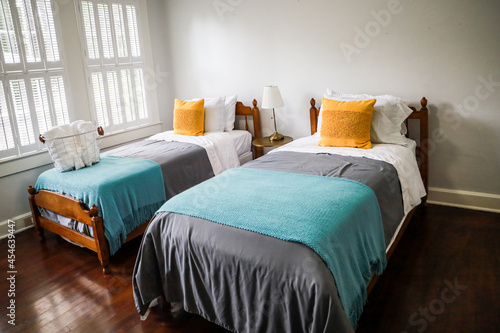 A guest bedroom with two twin beds with turquoise and gray bedspreads and yellow decorative pillows photo