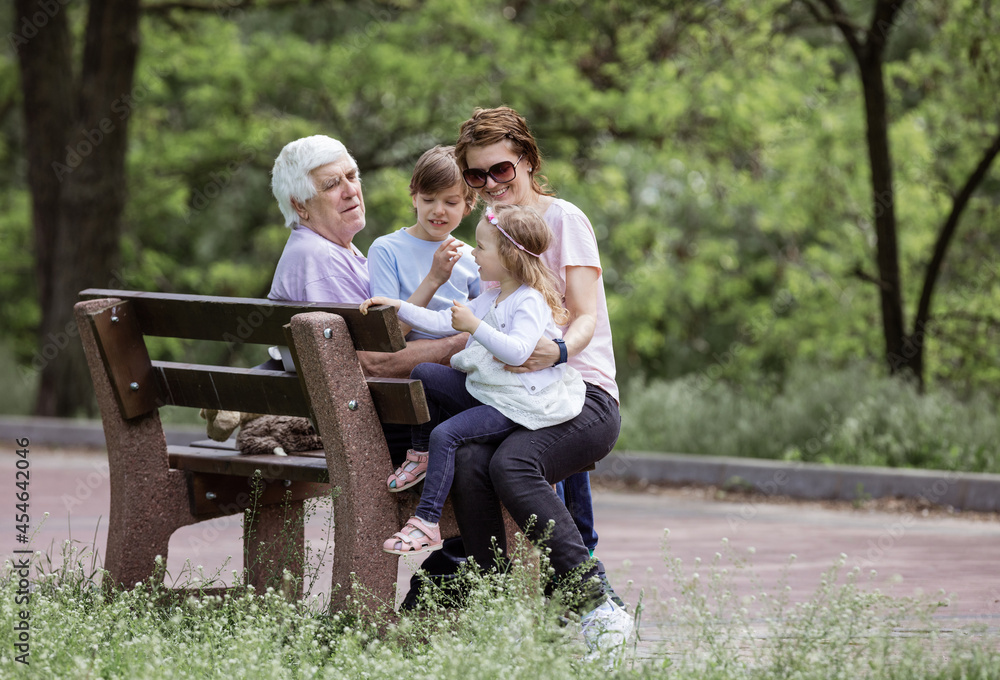 Three generation family in summer park: grandfather, mother, and grandchildren
