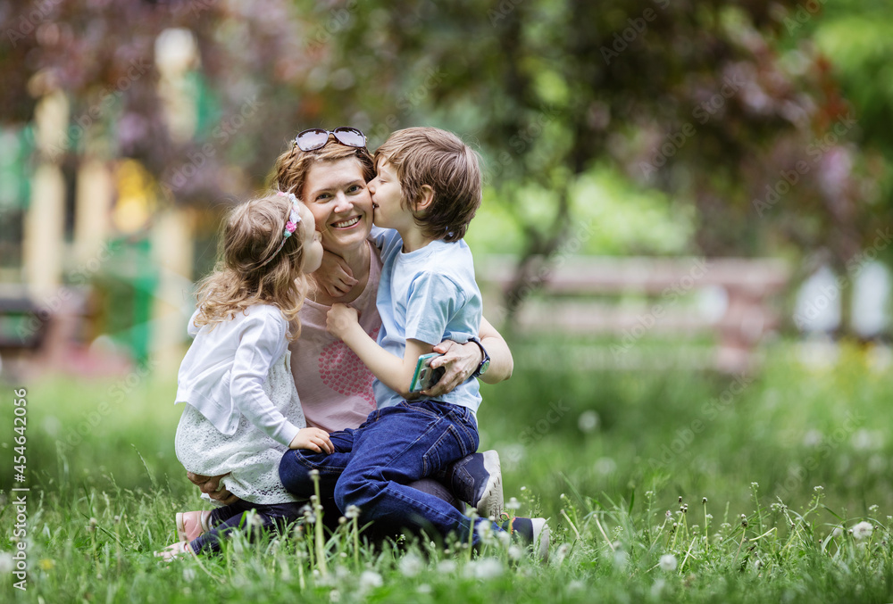 Young kids kissing mom while playing in park Young kids kissing mom while playing in park