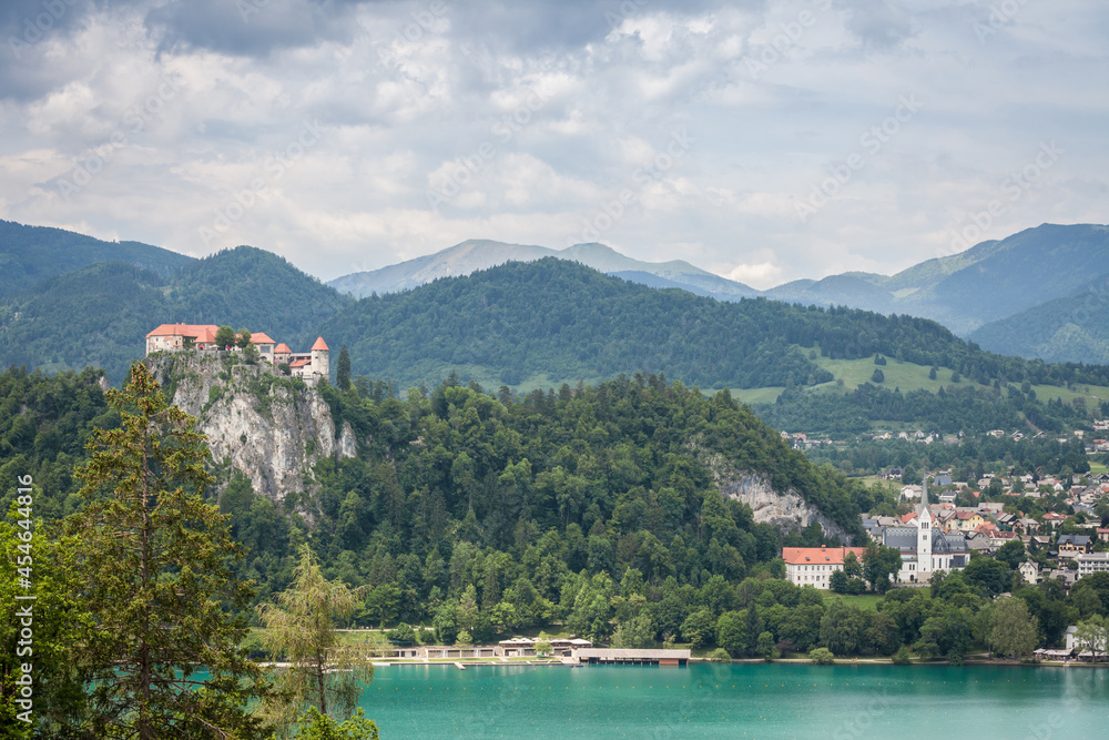 Panorama of the Bled lake, Blejsko Jezero, with its castle, Blejski Hrad, during a cloudy summer with the mountains of Julian alps. Bled Castle is a major monument of Slovenia.....