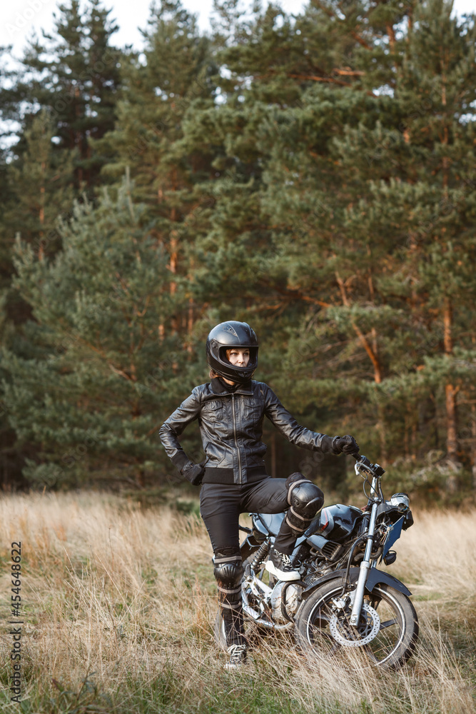 Obraz premium biker girl in black clothes and black helmet on a motorcycle