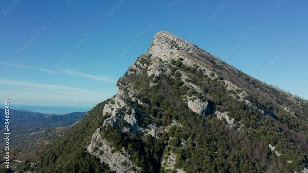 Aerial view over a large, rocky mountain, in middle of sunny, Italian wilderness - circling, drone shot Aerial view over a large, rocky mountain, in middle of sunny, Italian wilderness - circling, drone shot