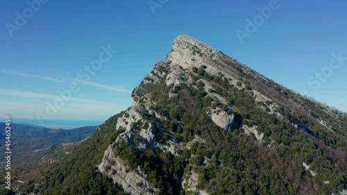 Aerial view over a large, rocky mountain, in middle of sunny, Italian wilderness - circling, drone shot photo