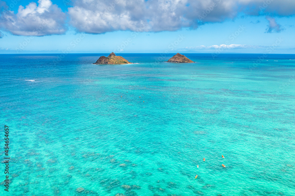 Fototapeta premium Aerial drone view of the Mokolua islands off the coast of Lanikai Beach in Oahu, Hawaii, USA. Water is turquoise, reef is visible, few white clouds in sky. 