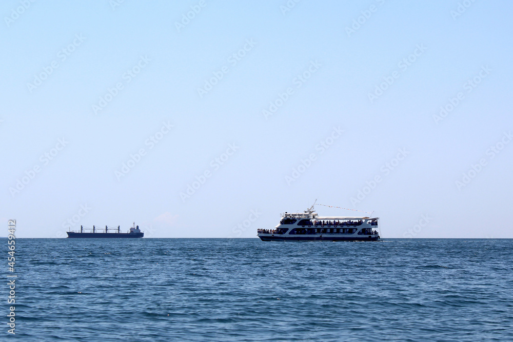 A steamer with tourists is sailing by the sea on a hot sunny day.