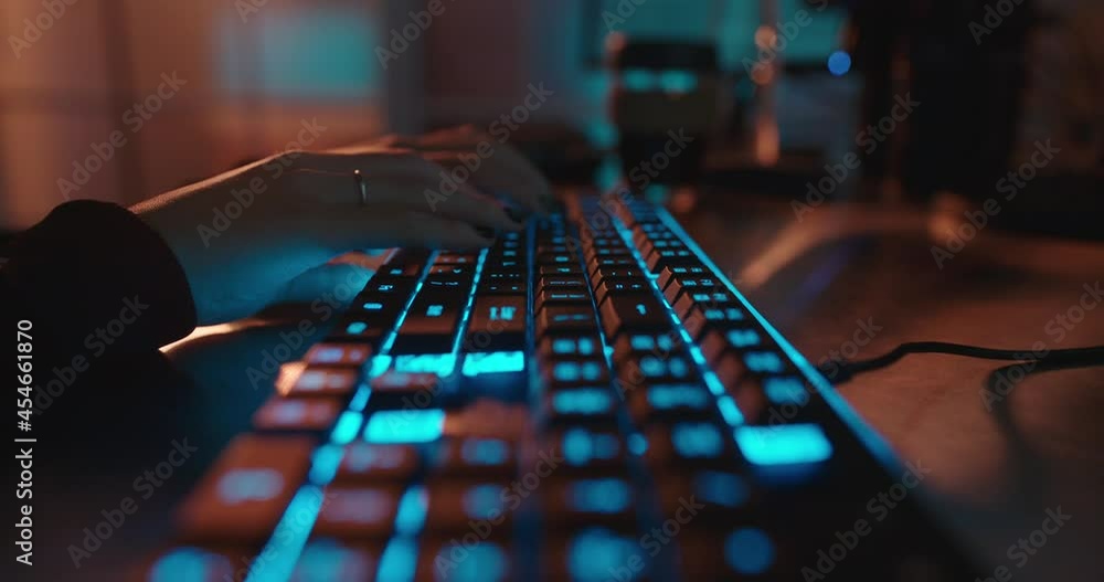 close up hands typing on keyboard programmer coding software gamer using keyboard with blue backlight playing game at night close up hands typing on keyboard programmer coding software gamer using keyboard with blue backlight playing game at night