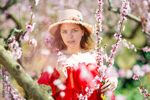 Portrait of happy girl in red dress in a blooming spring garden