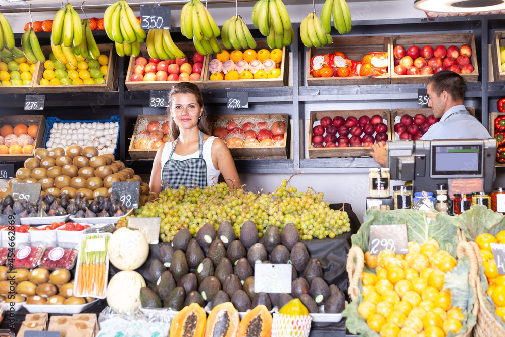 Posing cheerful woman and working man in fruit and vegetable shop