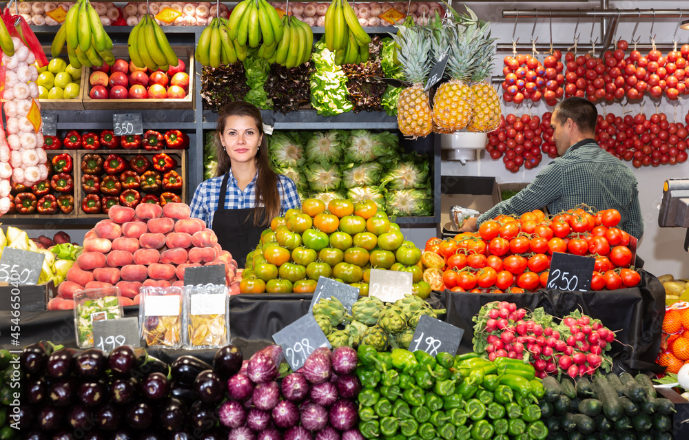 Posing young woman and working man in fruit and vegetable shop