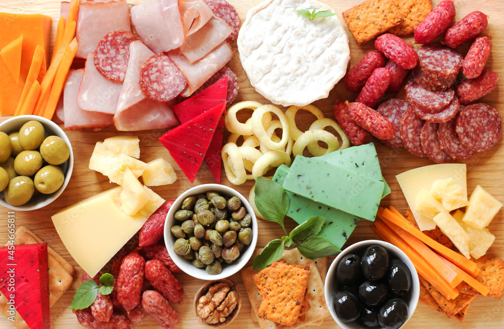 Charcuterie boards. Assorted meat, sausages, cheeses with nuts, olives, croutons on a wooden board. Food on a wooden background. View from above. 