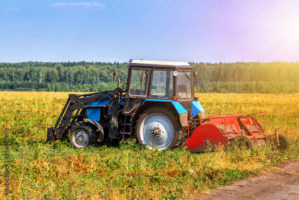 Modern wheeled agricultural tractor with harvesting equipment on an field Modern wheeled agricultural tractor with harvesting equipment on an field