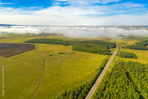 Fog rising in an early summer morning over the fields and the road. Siberia  Russia 
