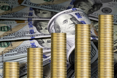 Growing piles of golden coins. Business concept. One hundred us dollar bills  as a background