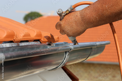 Dachdecker bei Spenglerarbeiten an einer Dachrinne photo