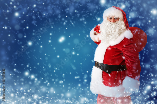 Santa Claus with bag full of gifts on color background © Pixel-Shot