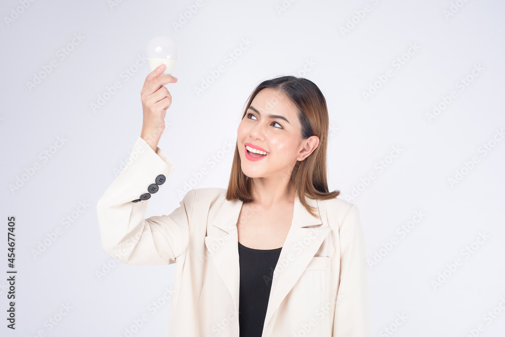 A young businesswoman is holding Light bulb wearing suit over white background studio A young businesswoman is holding Light bulb wearing suit over white background studio