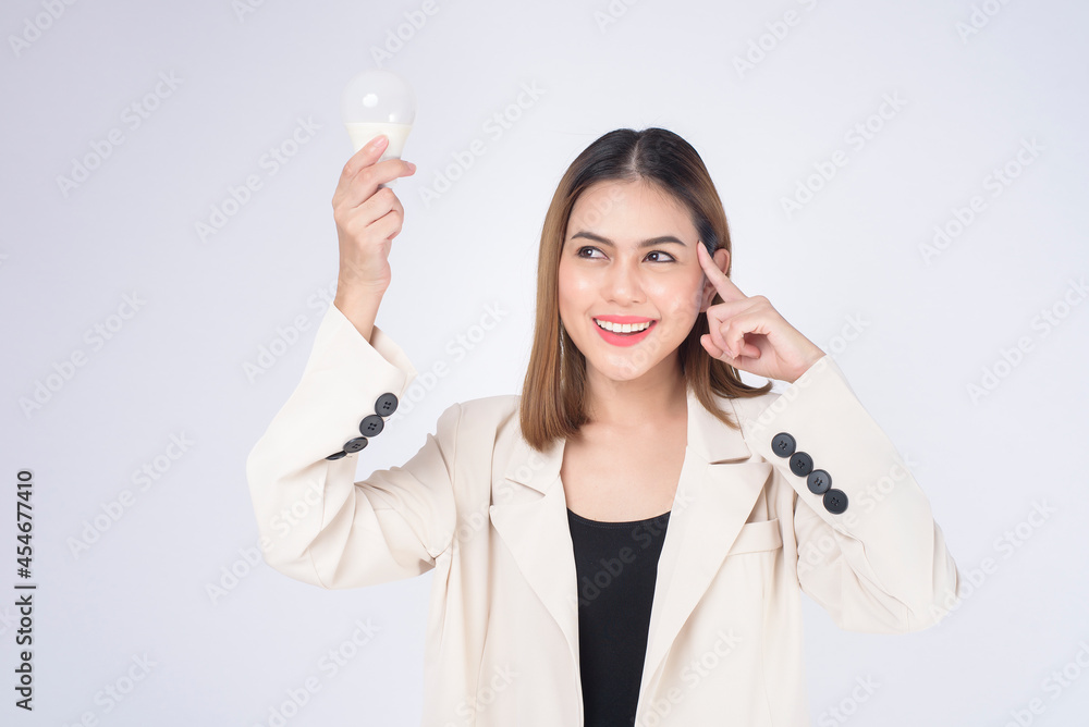 A young businesswoman is holding Light bulb wearing suit over white background studio A young businesswoman is holding Light bulb wearing suit over white background studio