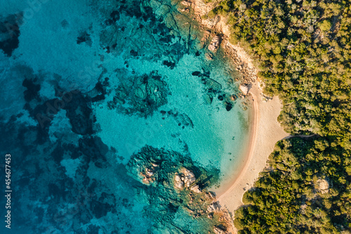 View from above, stunning aerial view of a green coastline with some beaches bathed by a turquoise sea during a beautiful sunrise. Liscia Ruja, Costa Smeralda, Sardinia, Italy.