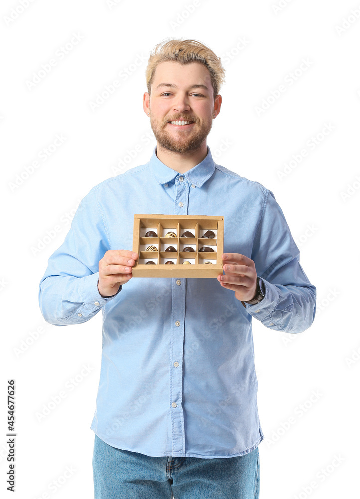 Handsome young man with box of chocolate candies on white background Handsome young man with box of chocolate candies on white background