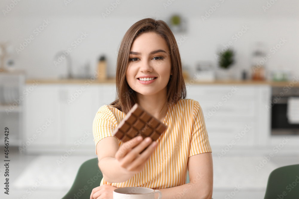 Beautiful young woman with tasty chocolate in kitchen Beautiful young woman with tasty chocolate in kitchen