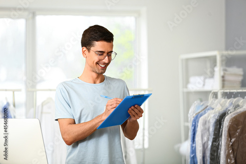 Male worker writing in clipboard at modern dry-cleaner's