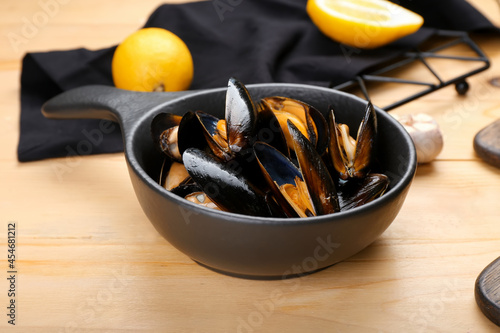 Frying pan with tasty mussels on wooden background