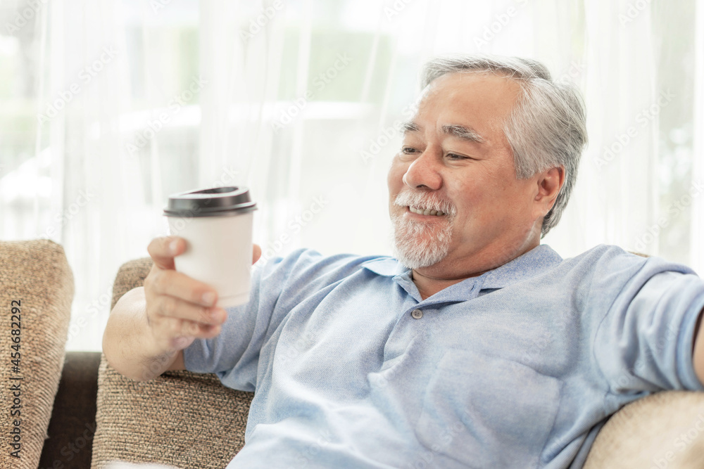 Senior Asian man feel happy drinking hot coffee , hot latte , hot cappuccino , Enjoy a cup of coffee on couch in the living room - lifestyle senior happiness concept Senior Asian man feel happy drinking hot coffee , hot latte , hot cappuccino , Enjoy a cup of coffee on couch in the living room - lifestyle senior happiness concept