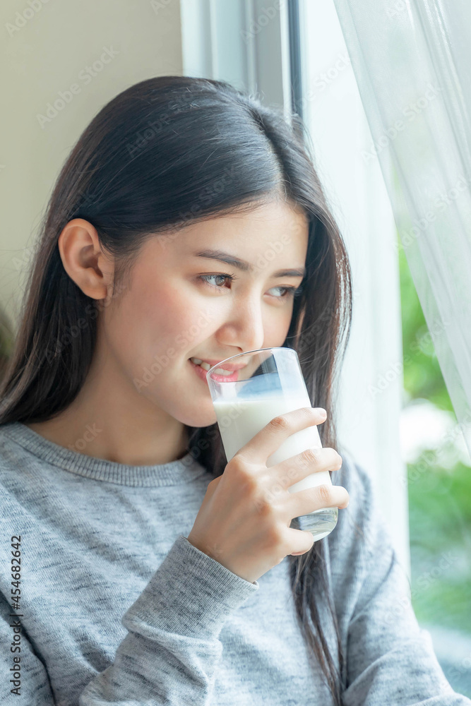 Beautiful beauty Asian woman cute girl feel happy drinking milk for good health in the morning , enjoying time in her home white bedroom background - lifestyle beauty woman concept Beautiful beauty Asian woman cute girl feel happy drinking milk for good health in the morning , enjoying time in her home white bedroom background - lifestyle beauty woman concept