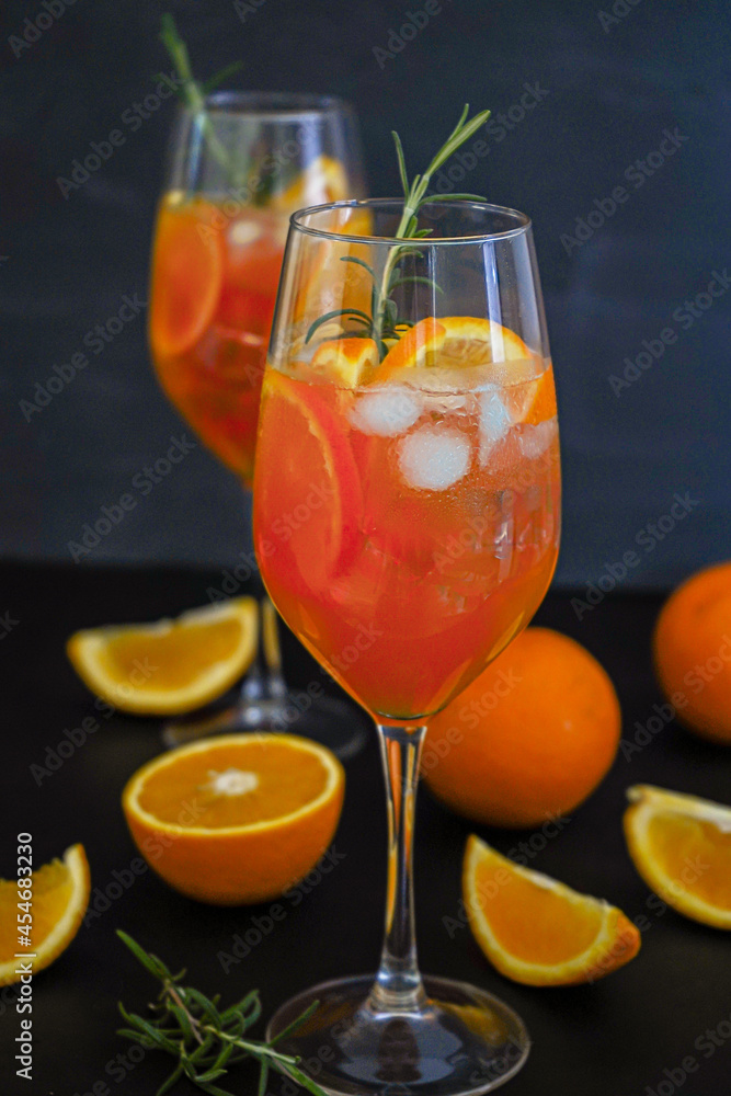 Fototapeta premium Aperol spritz is a summer drink served in a glass with aperol, prosecco, soda and orange slice. Glasses of icy cocktail in a wine glass at the bar. Black background. Refreshing drinks concept