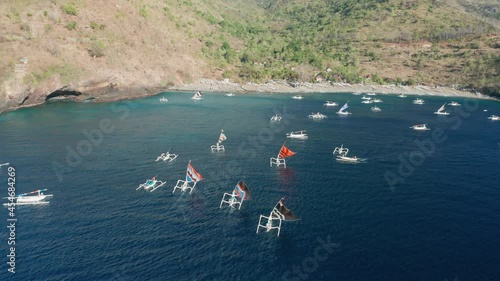 Traditional Jukung fishing boats returning to Pantai Kusambi beach, crab claw sail, aerial photo