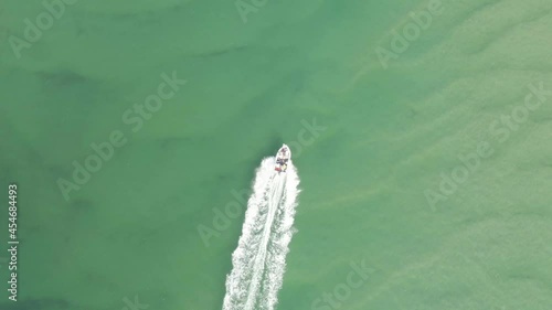 Aerial: Top down Footage of speed boat in Noosa lagoon with beautiful clear emerald water that flows down from the larger estuary system into the beach. Queensland, Australia. photo