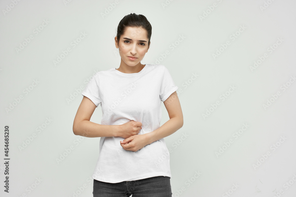Woman in white t-shirt holding her stomach diarrhea pain health problems