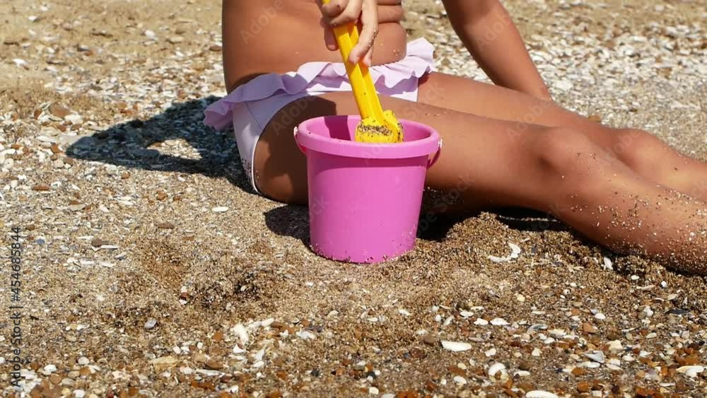 Little tanned girl playing with sand on the beach ocean sea. Summer vacation, travel. Little tanned girl playing with sand on the beach ocean sea. Summer vacation, travel.