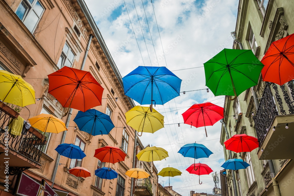 Colorful umbrellas hang between houses on the street